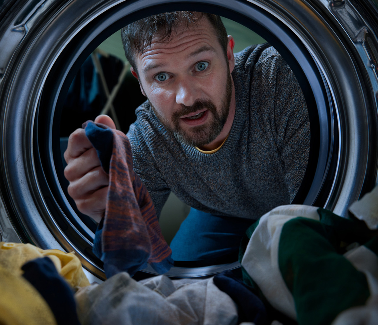 Man looking into the front load washing machine.